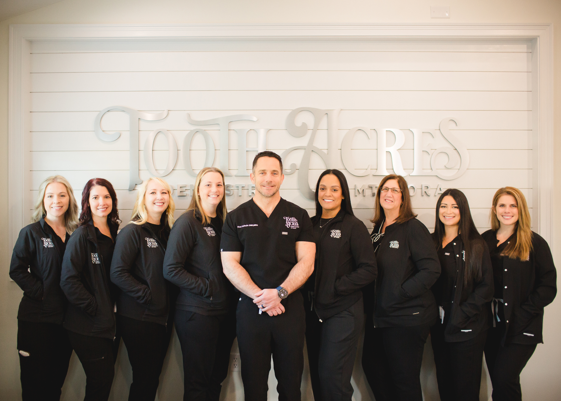 The Tooth Acres Dentistry team — Dr. Pellosie with hygienists, assistants, and front-desk staff in front of the Tooth Acres sign in Mount Dora, FL